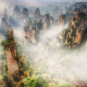 The Rock formations in Tianzishan area in Zhangjiajie National Park, Hunan province, China. Sunlight hitting the morning fogs in the valley.